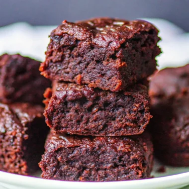 Close-up of stacked fudgy brownies showing a moist, gooey chocolate texture.